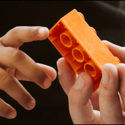 hand holding an orange lego block